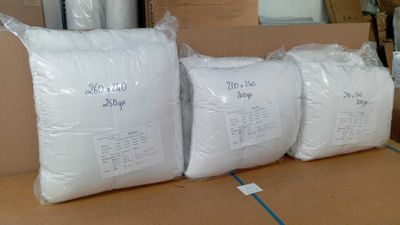 trois sacs contenant des oreillers blancs posés sur une boîte en carton