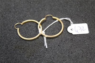 three pairs of gold hoop earrings with a price tag on a black surface