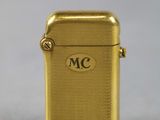a close up of a gold lighter on a white surface