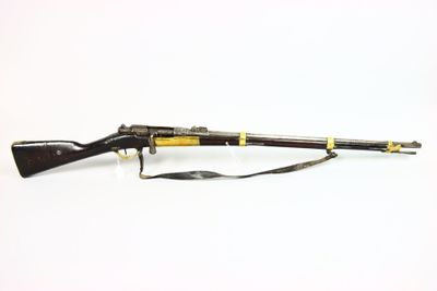 un vieux fusil au canon en bois, muni d'une bretelle, posé sur une surface blanche