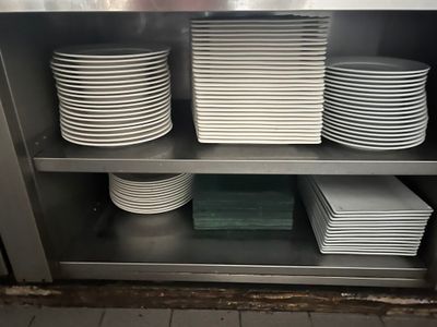 de nombreuses assiettes empilées sur une étagère métallique dans la cuisine