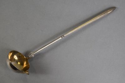 an antique silver spoon with a handle on a gray surface