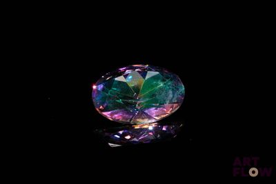 a close up of a colorful diamond on a black surface