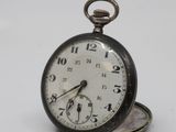 a silver pocket watch sitting on top of a white table