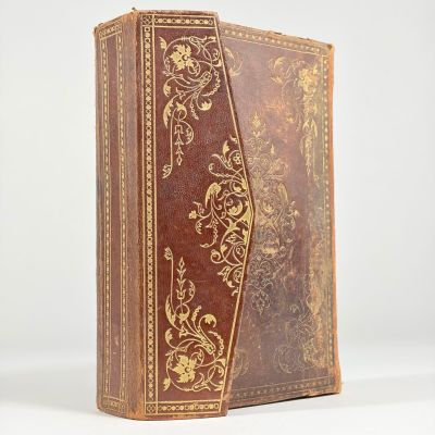un vieux livre à la couverture marron ornée de motifs dorés