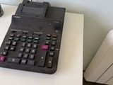 a black calculator sitting on a white table next to a lamp