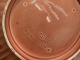 a brown cup sitting on top of a table next to a plate