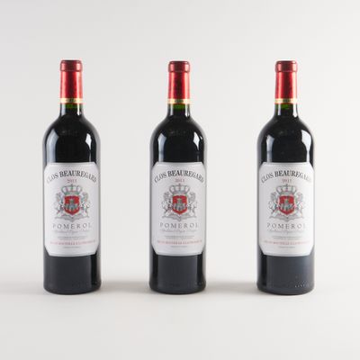 trois bouteilles de vin rouge sont alignées sur une surface blanche