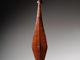 une sculpture en bois représentant un oiseau au long cou, posée sur une surface blanche