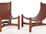 pair of brown leather lounge chairs with wooden legs on a white background