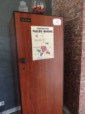 un réfrigérateur sur lequel est accrochée une affiche, devant un mur de briques