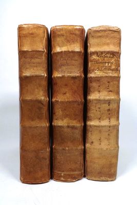 three old books are stacked on top of each other on a white surface