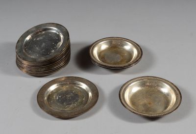 quatre assiettes en métal argenté et un saladier en verre posés sur une table