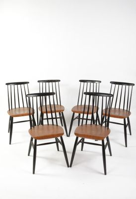 six chaises de salle à manger noires et en bois posées sur un sol blanc