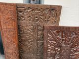 Plusieurs objets sculptés en bois sont posés sur une table près d'une fenêtre