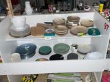 une étagère blanche sur laquelle sont posés de la vaisselle et d'autres objets