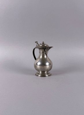 a small silver pitcher sitting on a white surface