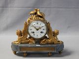 a gold clock sitting on top of a marble table