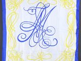 un gros plan sur un mouchoir blanc et bleu orné d'un monogramme bleu et jaune