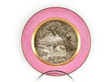 une assiette rose ornée d'un dessin, posée sur un socle