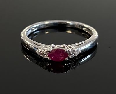 a close up of a ruby and diamond ring on a black surface