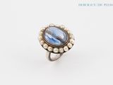 an image of a ring with a blue stone surrounded by pearls