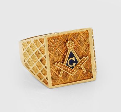 un gros plan d'une bague en or ornée d'un symbole maçonnique