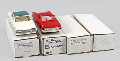 Plusieurs petites voitures sont posées sur des cartons, sur une surface blanche.
