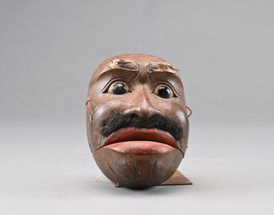 une sculpture en bois représentant un homme avec une moustache sur la tête