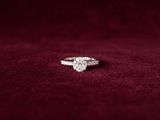 a close up of a diamond engagement ring on a red velvet background