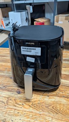 une friteuse à air chaud noire posée sur une table en bois