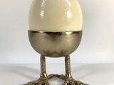 an egg sitting on top of a metal stand on a white surface