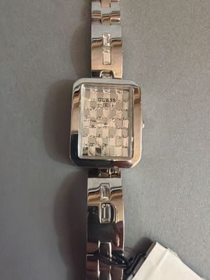 une montre-bracelet posée sur une table, avec une serviette blanche et une montre en argent