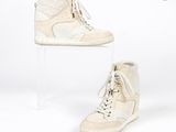 une paire de baskets blanches posée sur un socle en acrylique transparent, sur fond blanc