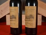 two bottles of red wine sitting next to each other on a table