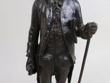 bronze statue of a man with a cane and a hat