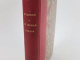un vieux livre à la couverture rouge posé sur une table blanche