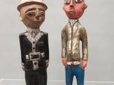 deux figurines en bois représentant des hommes debout l'un à côté de l'autre