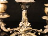 two silver candles are sitting on a table with a black background