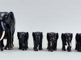 a group of black elephants standing in a row