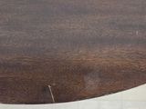 a wooden table with a round top on a tile floor