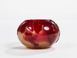 a red and yellow vase sitting on a white surface