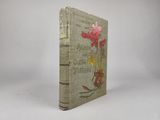 un vieux livre orné de fleurs, posé sur une surface blanche