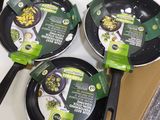 four frying pans sitting on top of a stove top next to a cardboard box