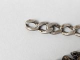 a silver bracelet with a chain on a white surface