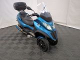 une photo d'un scooter bleu garé sur un sol à damier