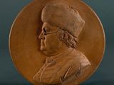 a close up of a bronze medallion with a man wearing a hat