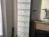 a tall filing cabinet in the corner of a room
