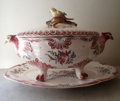 a bird sitting on top of a bowl on a saucer