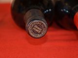 two bottles of wine sitting on a red cloth